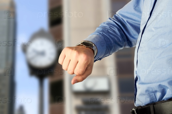 businessman checking time on his watch . Modern city behind