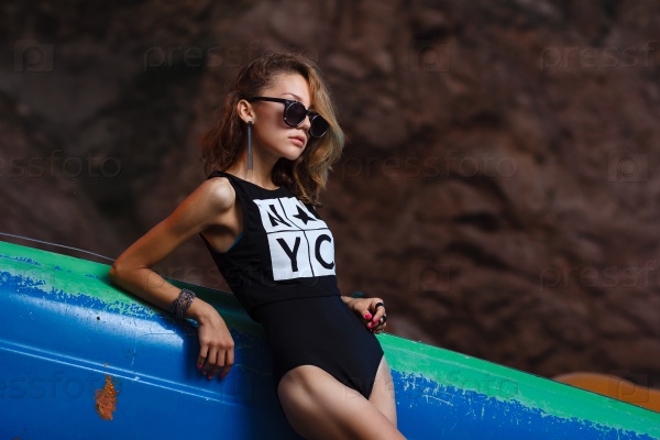 Beautiful young teen girl fashion shoot at sunset beach with catamaran, stock photo