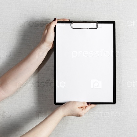 Blank paper poster in female hands. Clipboard with a blank paper. Mock-up for graphic designers portfolios, stock photo