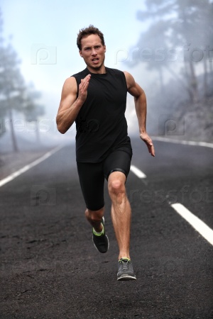 Running runner man sprinting workout on mountain road. Jogging male fitness model working out training for marathon on forest road in amazing nature landscape.