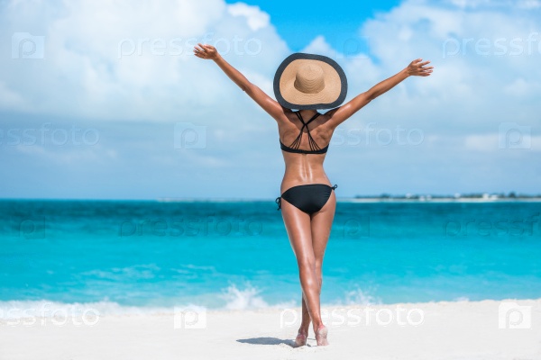 Summer vacation happiness carefree joyful sun hat woman with open arms in success enjoying body weight loss tropical beach destination. Holiday bikini girl relaxing from behind on Caribbean vacation.