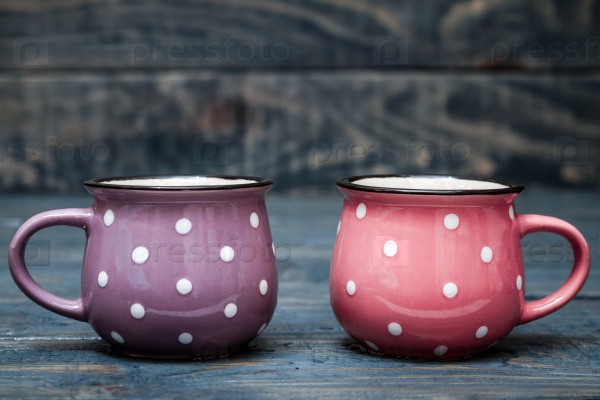 Pink and Purple Ceramic Mug with White Dots on Blue Wooden Background, stock photo