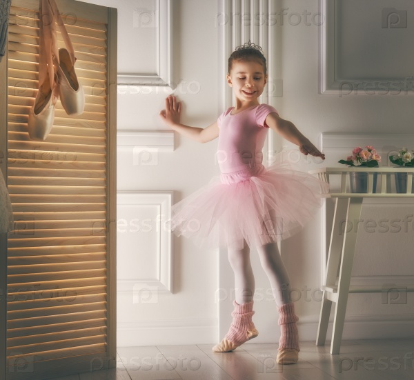 Cute little girl dreams of becoming a ballerina. Child girl in a pink tutu dancing in a room. Baby girl is studying ballet, stock photo