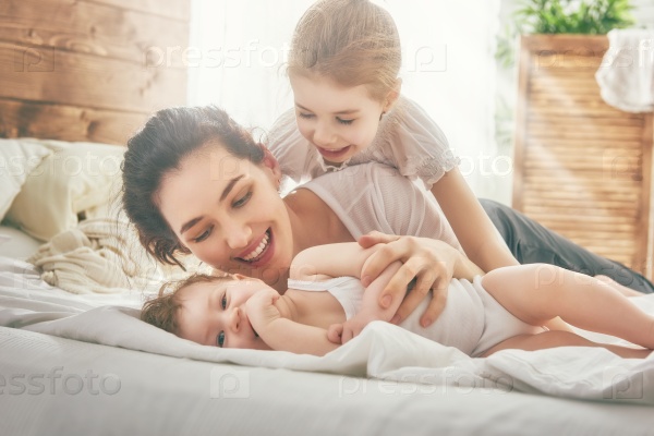 Happy loving family. Mother and her daughters children girls playing and hugging.