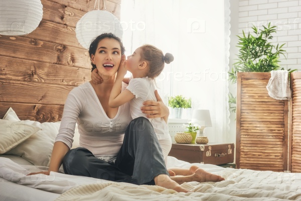 Happy loving family. Mother and her daughter child girl playing and hugging. Daughter whispering to mom a secret.