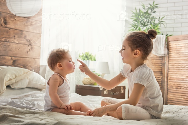 two cute child baby girls playing and having fun on the bed. loving sisters hug