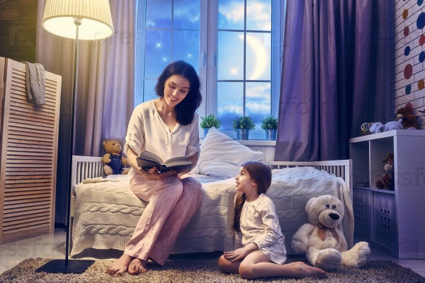 Family reading bedtime. Pretty young mother reading a book to her daughter.