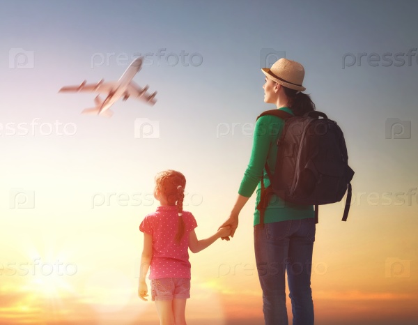 happy family at sunset. mother and her child daughter looking at the flying plane in the sky.