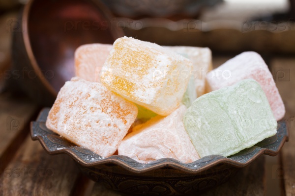 Lumps of Lokum or Turkish Delight in a tradition vase on wooden table close up , stock photo