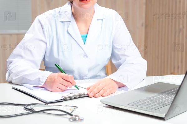 Woman in a white coat Doctor working at his desk in the office, stock photo