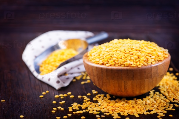 Yellow lentil in bowl and on a table, stock photo