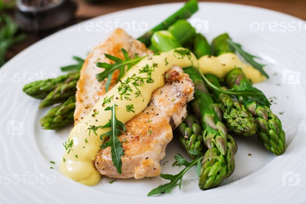 Baked chicken garnished with asparagus and herbs, stock photo