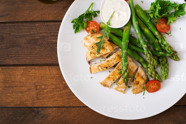 Baked chicken garnished with asparagus and tomatoes. Top view, stock photo