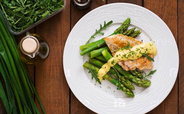 Baked chicken garnished with asparagus and herbs. Top view, stock photo