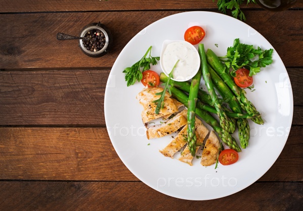 Baked chicken garnished with asparagus and tomatoes. Top view, stock photo