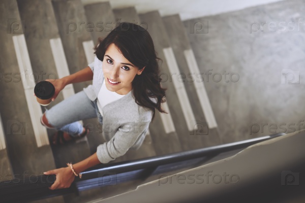 Portrait of lovely brunette walking up the stair, view from above