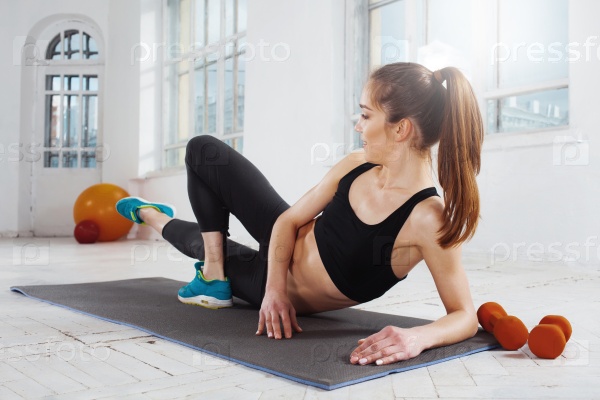 Beautiful young slim woman doing push ups at the gym with orange dumbbells, stock photo