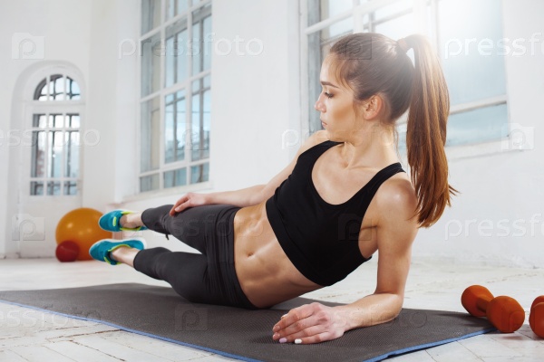 Beautiful young slim woman doing push ups at the gym with orange dumbbells, stock photo
