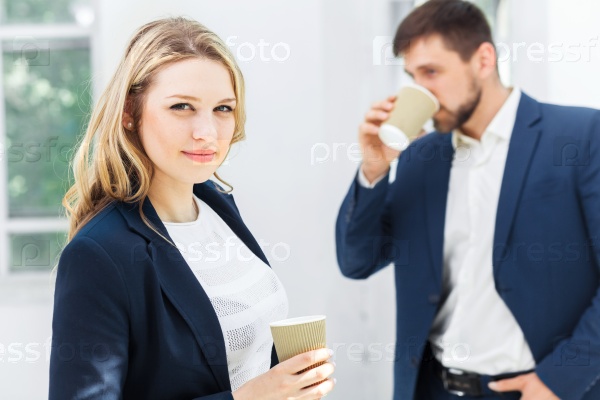 Young colleagues having coffee break, chatting in office, stock photo