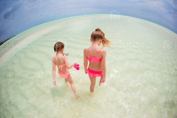 Adorable little girls having fun on the beach, stock photo