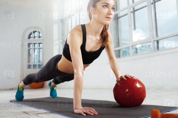 Beautiful young slim woman doing some gymnastics at the gym with medball, stock photo
