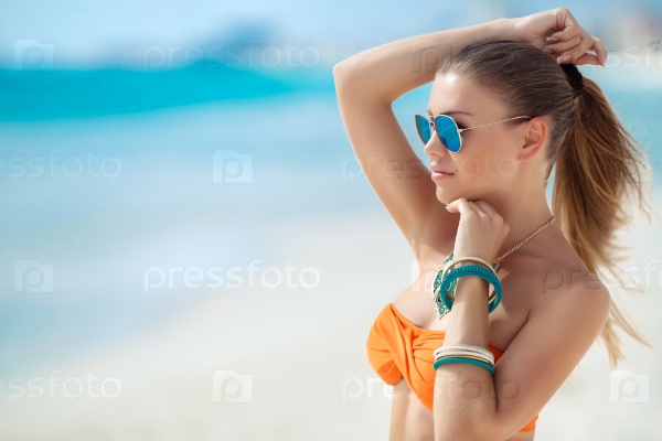 Happy young woman on the beach. Outdoor fashion portrait of glamour lady enjoying her vacation on luxury villa in hot tropical island. Sexy perfect fit body woman.