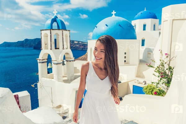 Santorini travel tourist woman on vacation in European destination walking on stairs. Asian girl in white dress visiting three blue domes in Oia village, greek island. Summer Europe holidays.