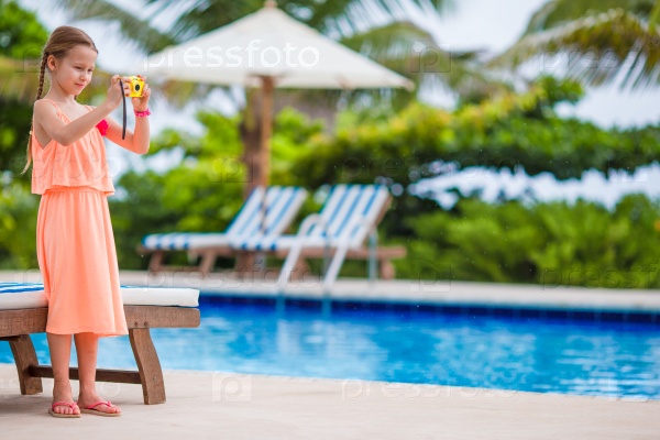 Adorable little girl making selfie near a swimming pool, stock photo
