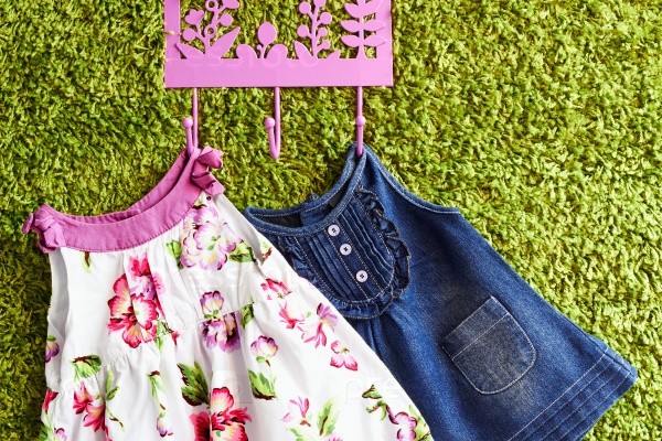 Fashion baby dresses  hanging on a hanger on a green background