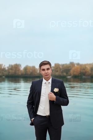 Stylish newlywed,Portrait of the groom in the park on their wedding day,the husband.\
elegant bride in an expensive suit.groom waiting for the bride