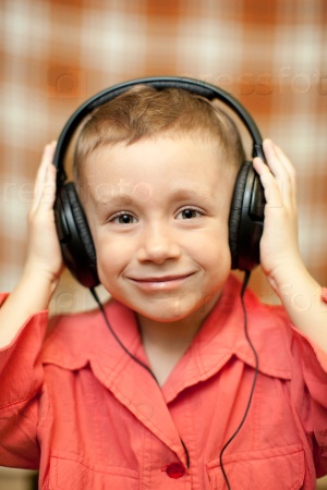 boy in red rkbashke listening to music through headphones, smiling boy,Close-up of a child listening to music with headphones