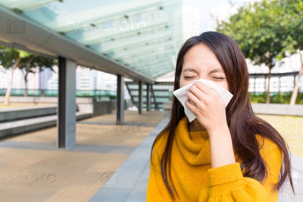 Asian young woman blowing nose