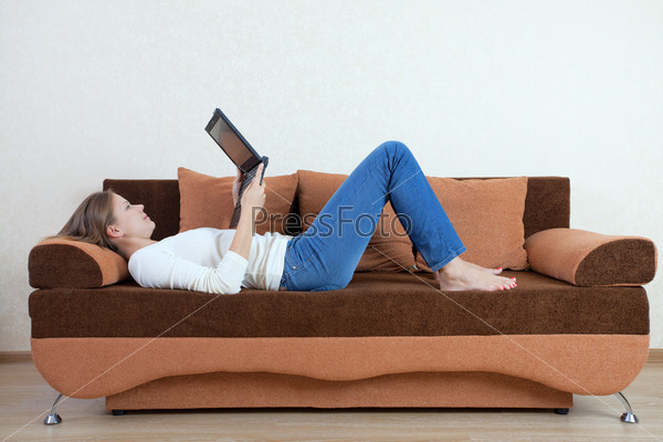 Фотография на тему Девушка лежит на диване с ноутбуком