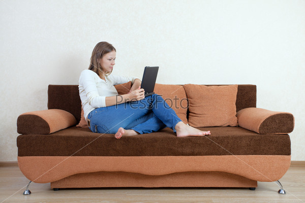 Фотография на тему Девушка сидит на диване с ноутбуком