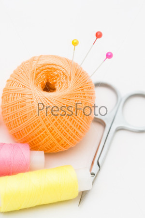 Швейные принадлежности - нитки, ножницы, иглы, пуговицы, ленты на ткани. Концепция пошива.