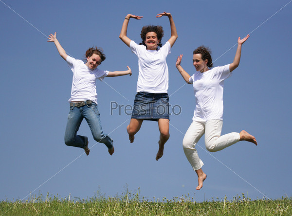 Две счастливые девушки прыгают в воздух и веселятся на снегу в солнечный зимний день