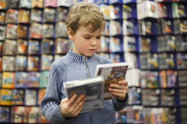 Мальчик выбирает один из двух DVD в специализированном магазине - paha_l