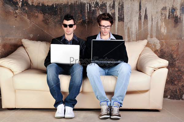 Фотография на тему Двое мужчин сидят на диване с ноутбуками