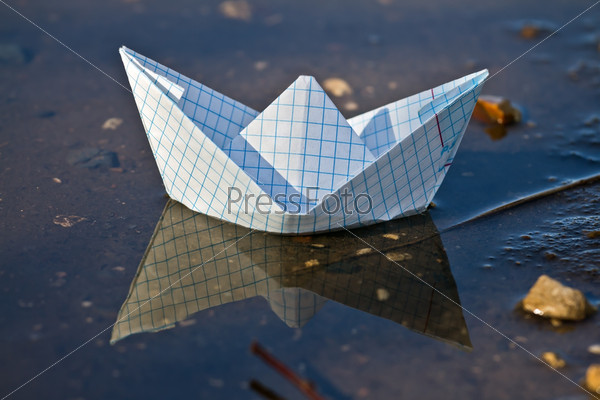 Бумажный кораблик, плывущий по весеннему ручью