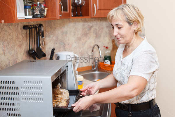 Фотография на тему Зрелая женщина готовит в кухне | PressFoto