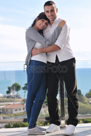 Счастливая пара, стоя на балконе, пили кофе.