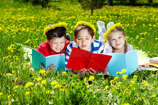Фотография на тему Дети читают книги на лужайке | PressFoto