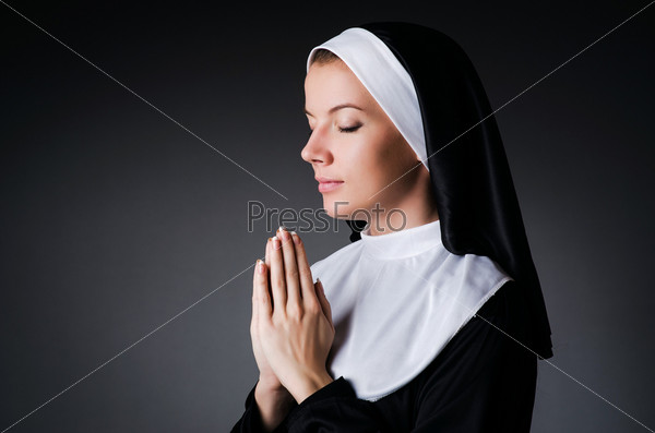 Фотография на тему Портрет молодой монахини в очках с Библией на черном фоне | PressFoto