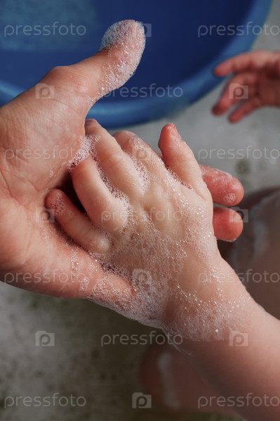 мама держит за руку малыша в ванне