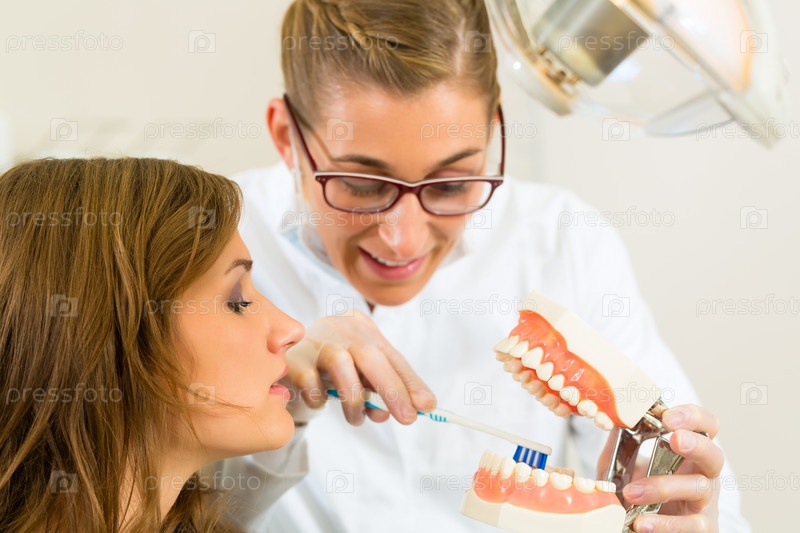 Фотография на тему Стоматолог с зубным протезом объясняет как чистить ...