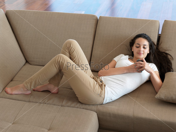 Фотография на тему Девушка с телефоном лежит на диване