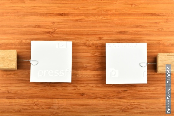 Two Paper Notes With Holders In Different Directions On Wood