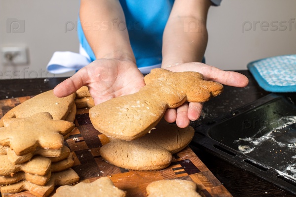 Девочка держит противень со свежеиспеченным имбирным печеньем