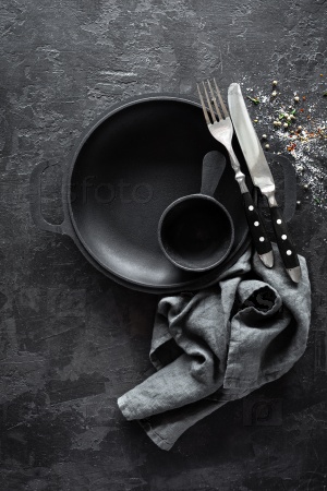 Пустая чугунная сковорода со столовыми приборами