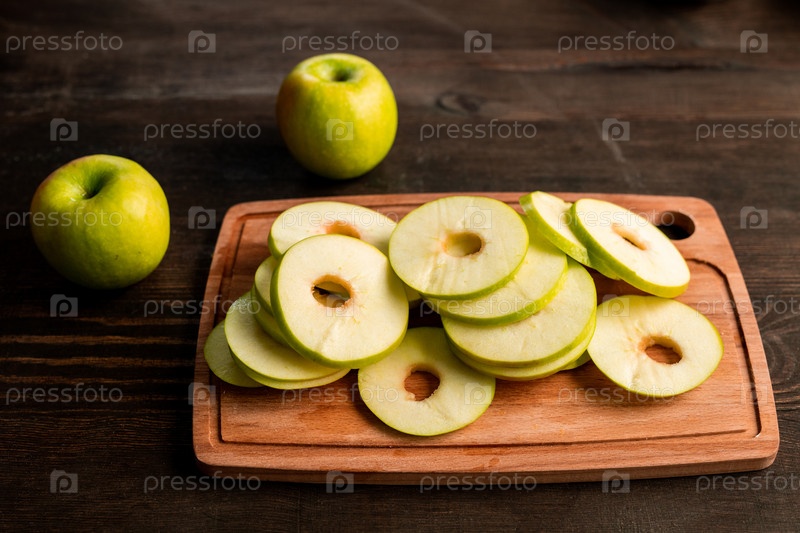 Pile of fresh green apples ready to be put on fruits dryer on cutting board